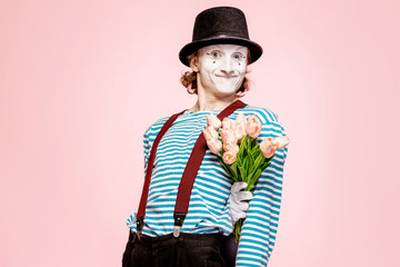Emotional pantomime posing with tulip bouquet on the pink background indoors. Valentine's Day and...