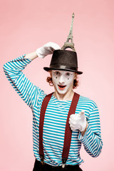 Pantomime with white facial makeup posing with Eiffel tower on the pink background. French mime...