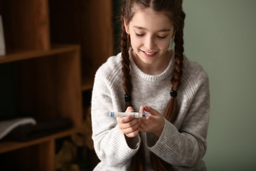 Diabetic girl taking blood sample with lancet pen at home
