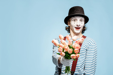 Emotional pantomime posing with tulip bouquet on the blue background indoors. Valentine's Day and...
