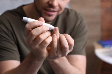 Diabetic man taking blood sample with lancet pen at home