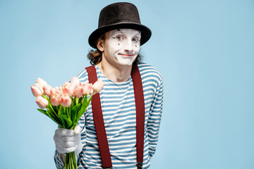 Emotional pantomime posing with tulip bouquet on the blue background indoors. Valentine's Day and...