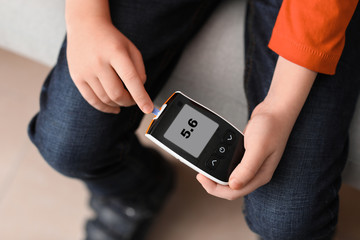 Diabetic child with digital glucometer at home, closeup