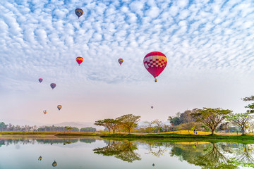 Fototapeta premium Colorful hot air balloons floating above the lake in Chiang Rai, Thailand