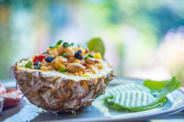 Fried rice with seafood served in a pineapple with colorful background.