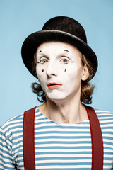 Close-up portrait of an actor as a pantomime with white facial makeup showing expressive emotions...