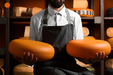 Male seller with delicious cheese in store