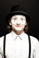 Close-up portrait of a pantomime with white facial makeup posing with expressive emotions on the...