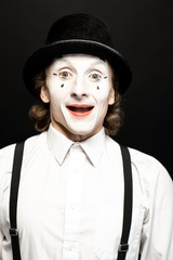 Close-up portrait of a pantomime with white facial makeup posing with expressive emotions on the...