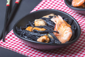 Seafood. Black homemade noodles of cuttlefish ink with mussels and shrimps. Asian cuisine