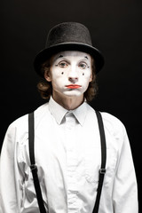 Close-up portrait of a pantomime with white facial makeup posing with expressive emotions on the...