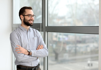 Portrait of young businessman near window in office