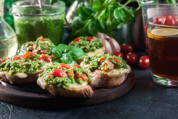 Bruschetta with fresh pesto, mozzarella and cherry tomatoes on cutting board