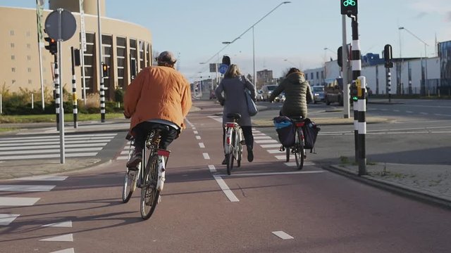 People on bicycles crossing city street. Slow motion of street crosswalk with people riding bicycles on red lane in sunlight 