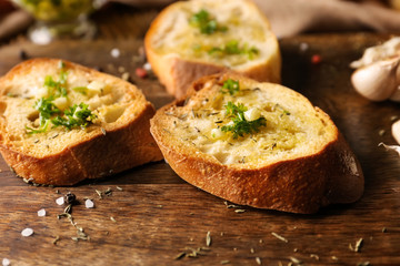 Sliced bread with olive oil, garlic and herbs on wooden table