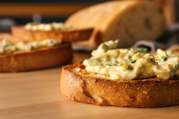 Sliced bread with garlic spreading on wooden table, closeup