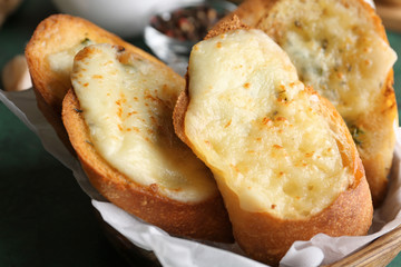 Sliced bread with garlic and cheese on table, closeup