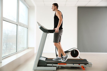 Fototapeta premium Sporty young man on treadmill in gym
