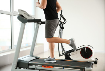 Fototapeta na wymiar Sporty young man on treadmill in gym
