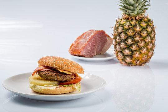 cheeseburger with pineapple on a plate with fresh bacon and ripe pineapple