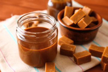 Jar with liquid caramel on table