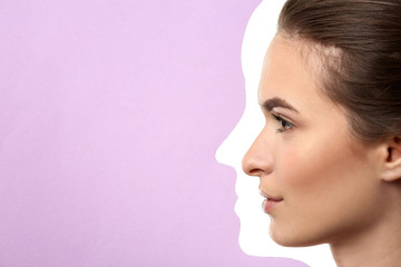 Young woman with beautiful eyebrows visible through hole in color paper