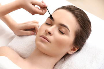 Obraz na płótnie Canvas Young woman undergoing eyebrow correction procedure in beauty salon