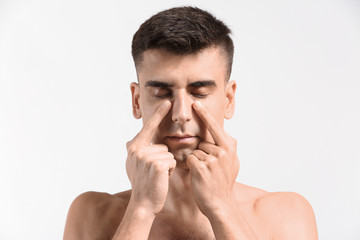 Naklejka premium Man giving himself face massage on light background