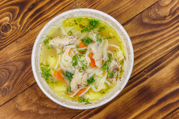 Chicken soup with noodles and vegetables on wooden table. Top view