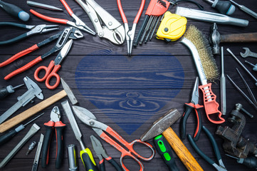 Tool and heart on dark wooden background. Love for your work, Father's Day.
