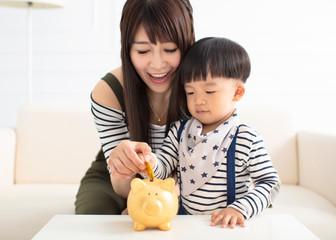 boy and mother putting a coin in to  piggy bank