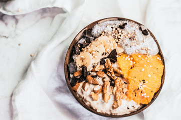 Healthy oatmeal bowl with fruits, nuts and chocolate chips. Breakfast idea, top view flat lay