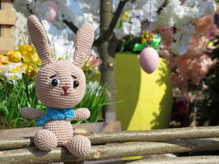 Easter Bunny on background of spring decorations. Festive card with knitted toy rabbit, easter eggs...
