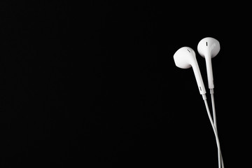 White Earbuds or Earphones on black background. Copy paste space