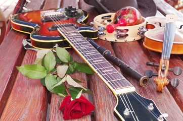 Electric guitar, pipes, maracas and a red rose on a wooden table
