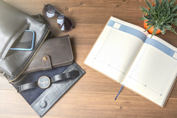 Business accessories on desktop: notebook, bag, watch, pen, cufflink and phone. Success in business.