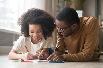 Caring black dad drawing with colored pencils teaching child girl 