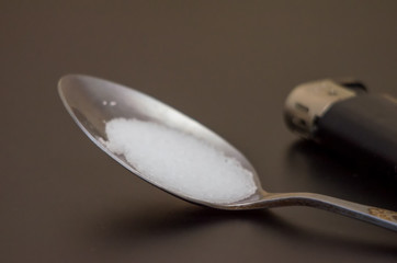 spoon with drugs for heroin cooking on dark table. Drug addiction concept