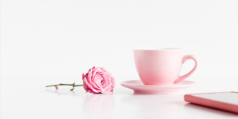 Cup of coffee, rose flower and phone on white background, copy space