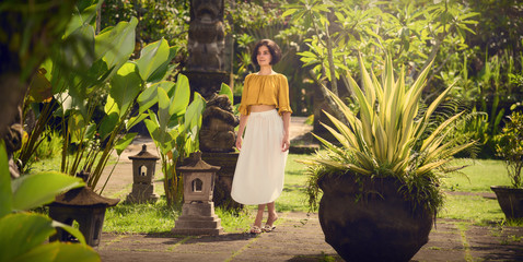 A girl in a white dress. Travel to Bali. Authentic architecture.	 Travel.