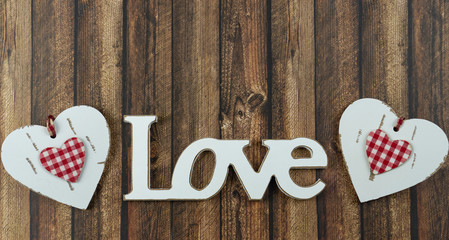 The word love in wooden letters with a white heart beside, wooden background