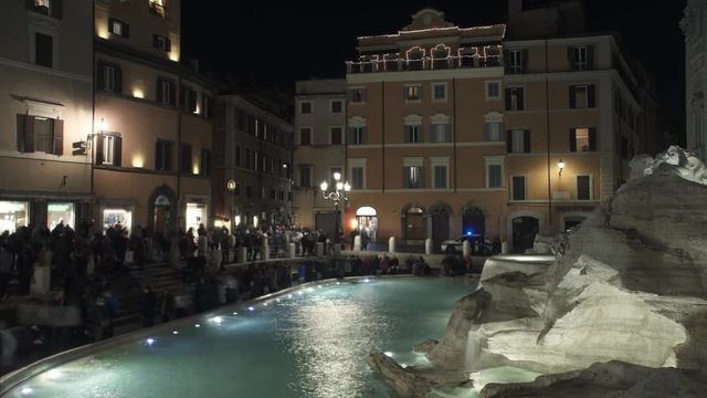 Timelapse of tourists sitting walking around Trevi fountain at night time in Rome. Tourists taking photos around Fontana di Trevi in Rome in the evening. ITALY6 2018