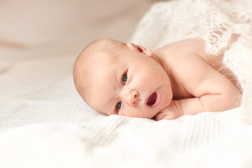 surprised newborn babe lying on the bed.