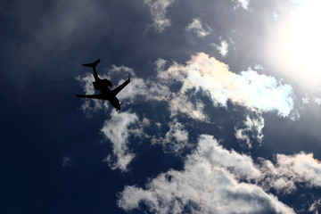 Naklejka na ściany i meble A jet airliner flying under the sun shining in the sky