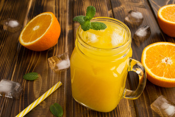 Orange juice with ice in the glass on the brown  wooden background