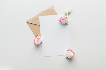 top view of empty blank with brown craft paper envelope and eustoma on grey background