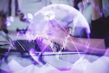 Hands typing on laptop. Business and Financial concept. Double exposure of stock market charts.