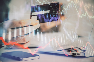 Hands typing on laptop. Business and Financial concept. Double exposure of stock market charts.