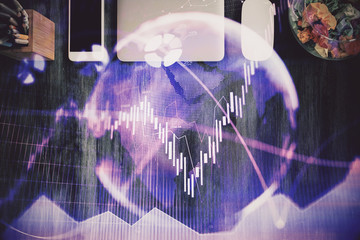 Double exposure of stock market chart and office desktop on background. financial strategy concept.