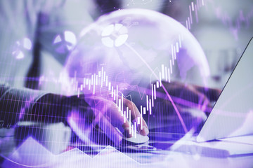 Hands typing on laptop. Business and Financial concept. Double exposure of stock market charts.